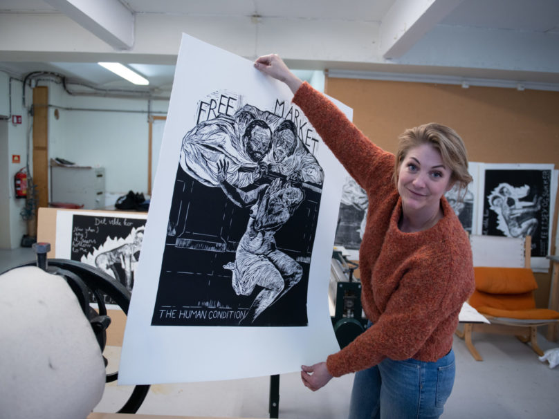 Kunstner Julie Ebbing holder oppe et av sine grafiske verk
