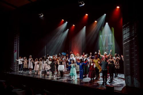 En stor gruppe barn og unge står på en scene og synger som del av forestillingen Vi i Namsos